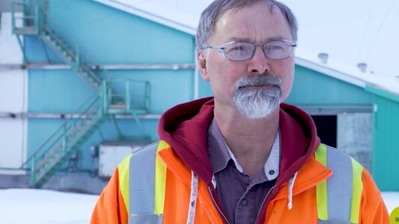 An elderly man in a construction uniform infront of a farming facility paired with the Darcy H article