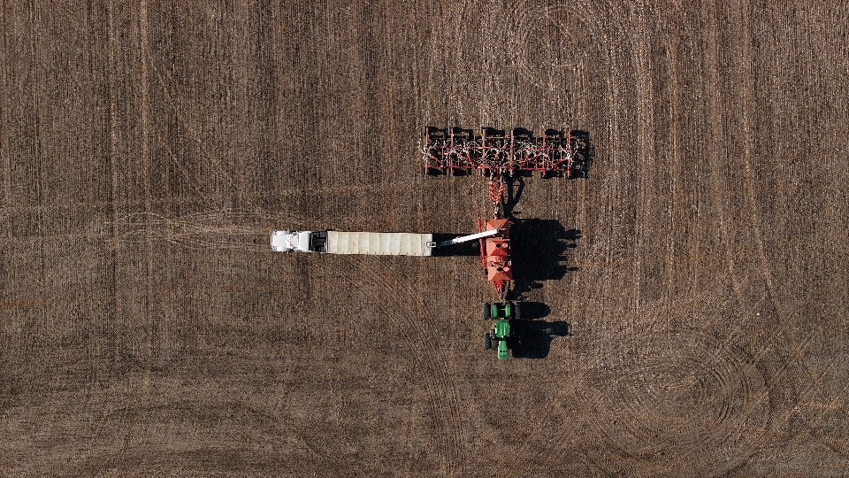 Aerial views of a farmer preparing their equipment for fertilizer application.