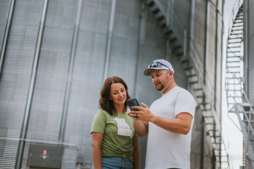 Two farmers using digital farm planning tools on a smartphone to help manage operations and improve crop decisions.